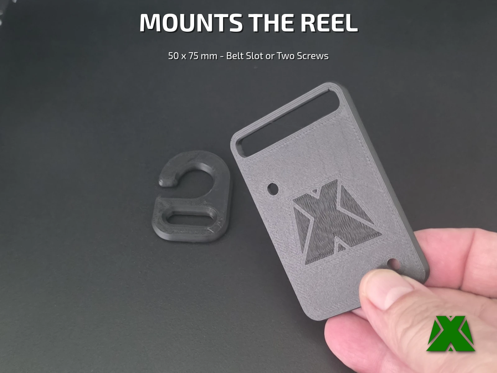 The mounting plate held in a hand, its belt slot along the top edge and the embossed MakerX X across the face, with the hook lying beside it