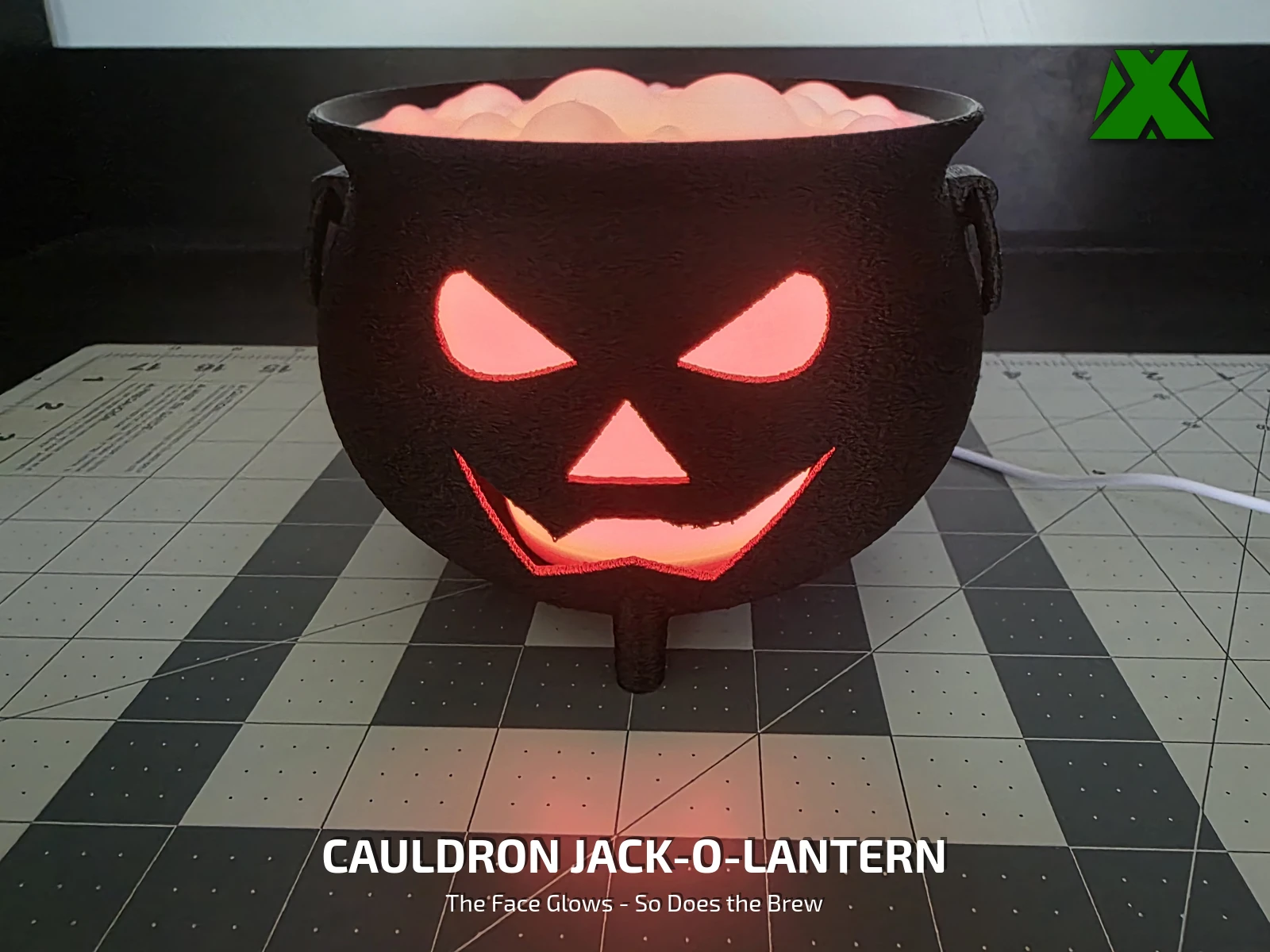 The finished cauldron lit red with the lid off, its carved face glowing and the bubbling brew glowing above the rim