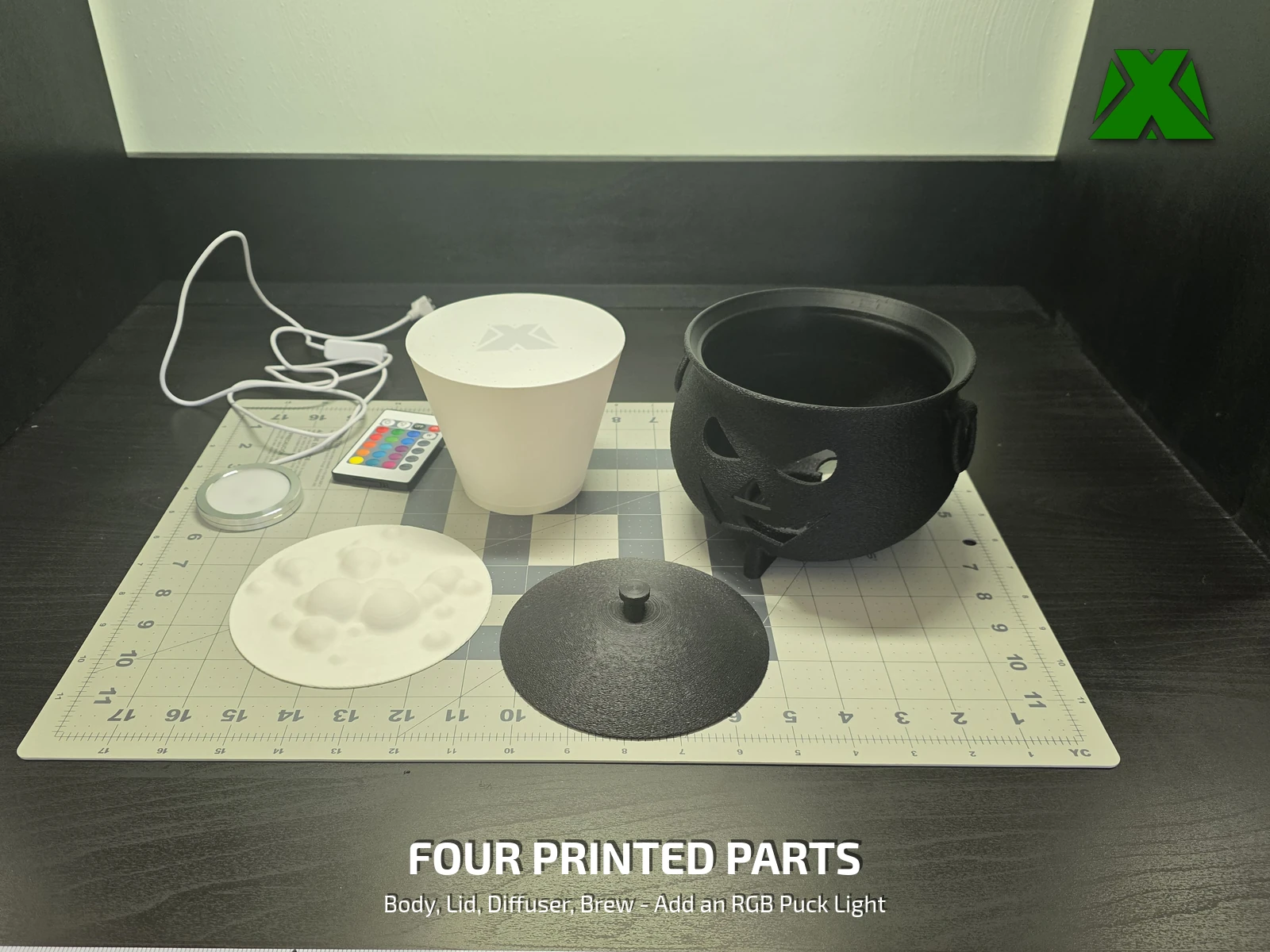 The four printed parts laid out on a cutting mat beside an RGB puck light, its remote and its USB lead