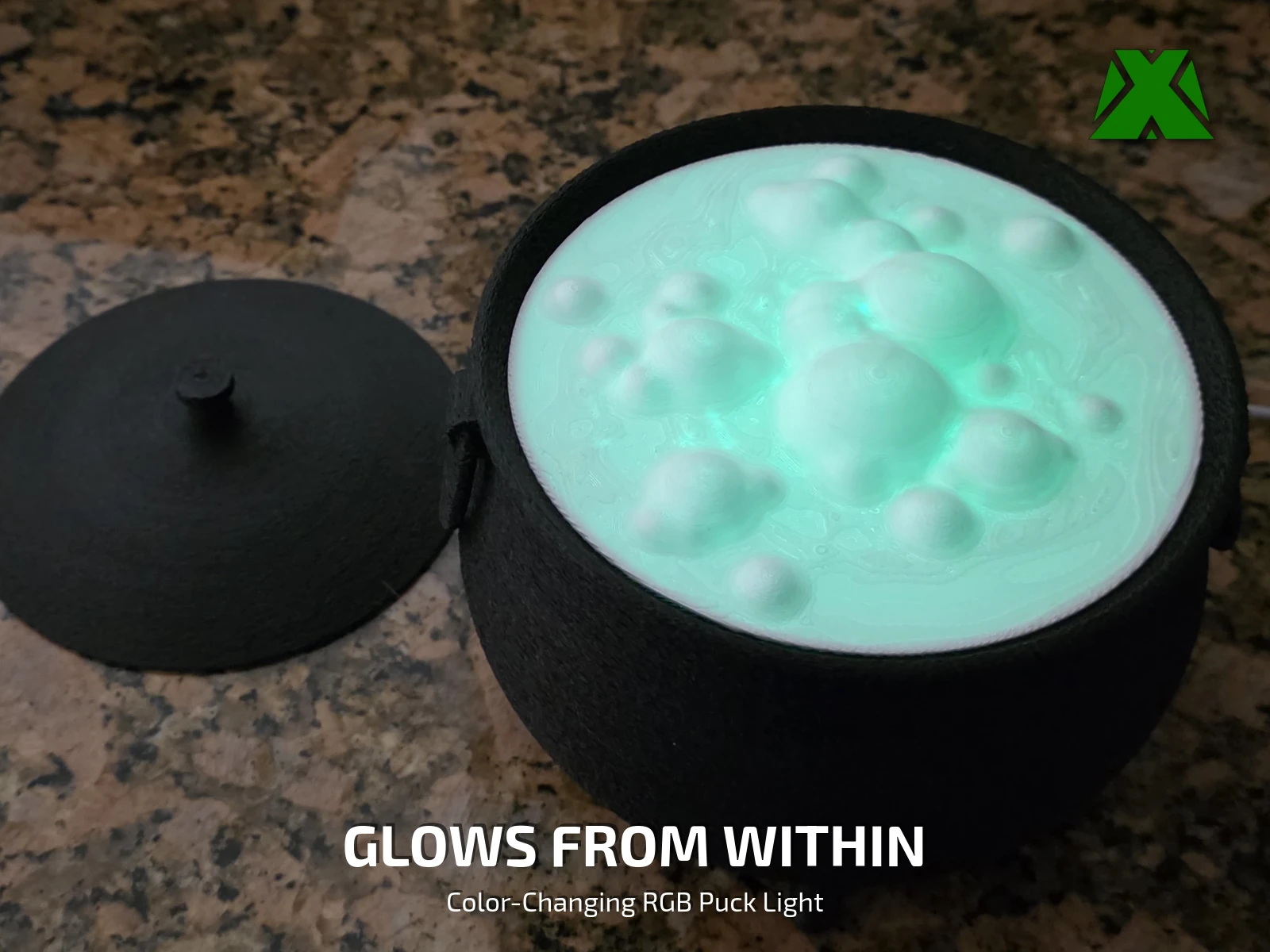 The cauldron lit from inside with a teal glow, the domed bubbles of the insert catching the light, lid resting beside it