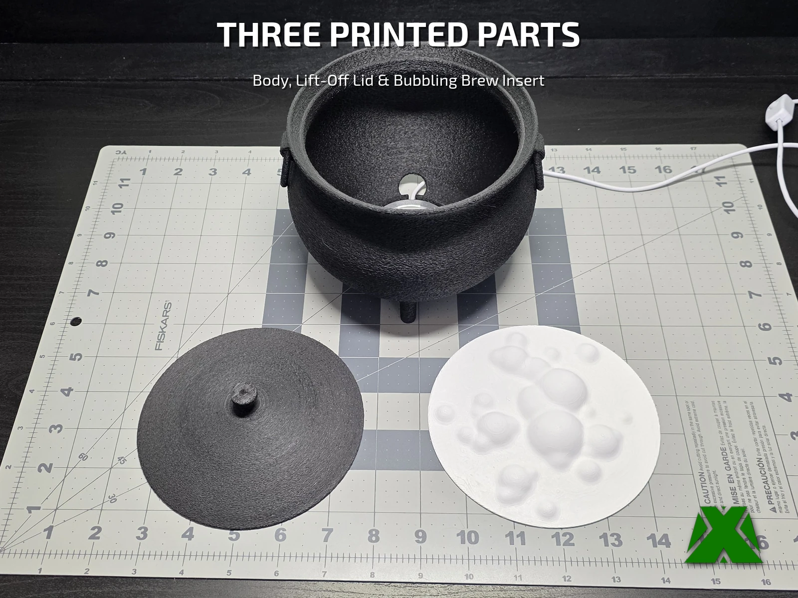 All three printed parts laid out on a cutting mat with an inch ruler: the cauldron body, the lid, and the white bubble insert