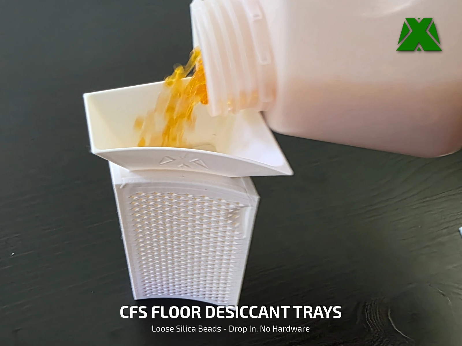 Orange silica beads pouring from a jug through a printed funnel lid into a perforated tray