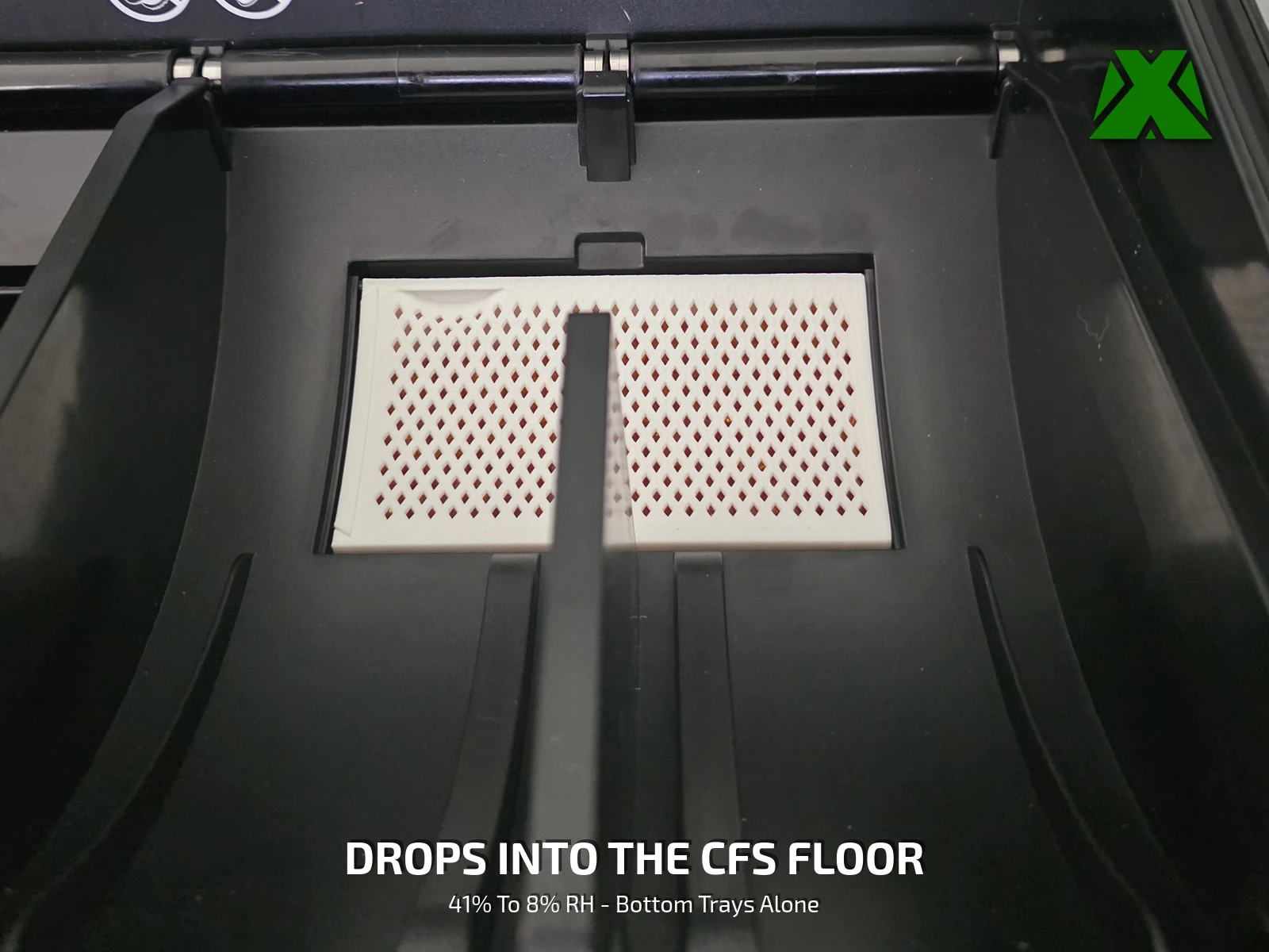 Two trays seated either side of the center rib in the floor bay of a Creality CFS, their mesh faces flush with the floor