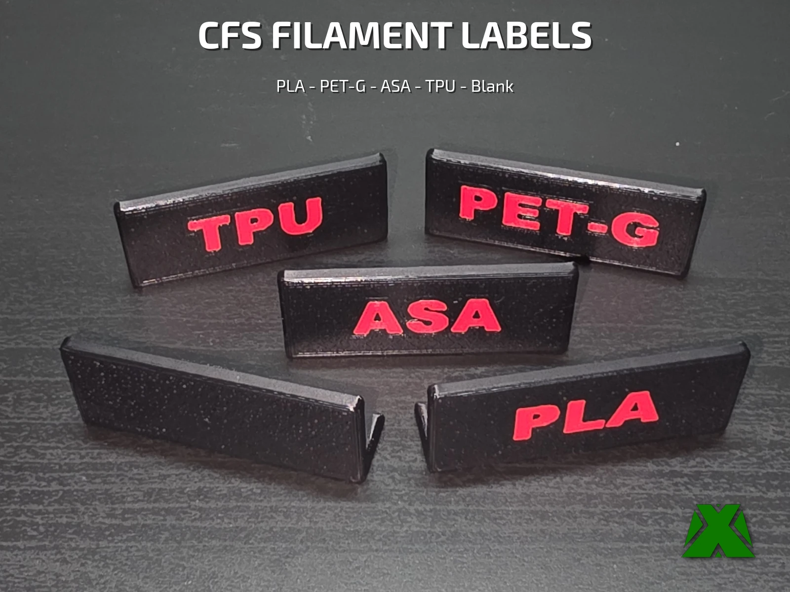 Five printed CFS labels laid out on a dark surface, black tags with red PLA, PET-G, ASA and TPU lettering