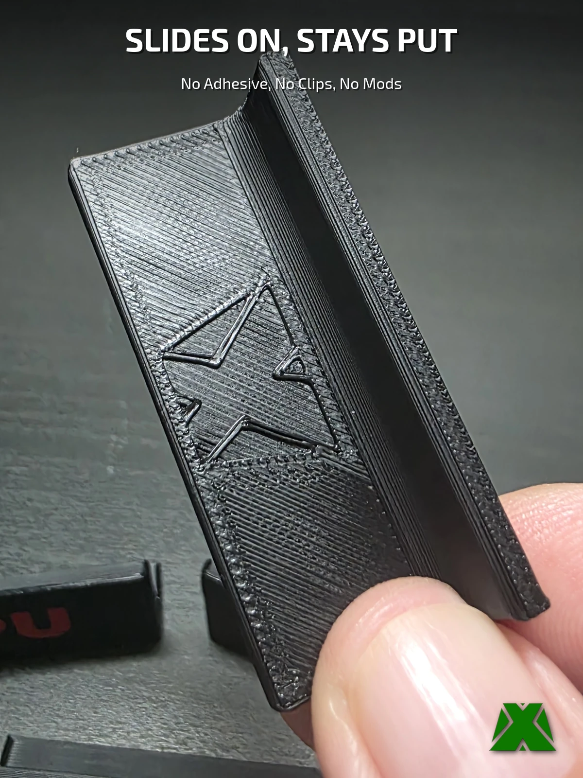 A label held between finger and thumb, showing the slide-on channel on its underside