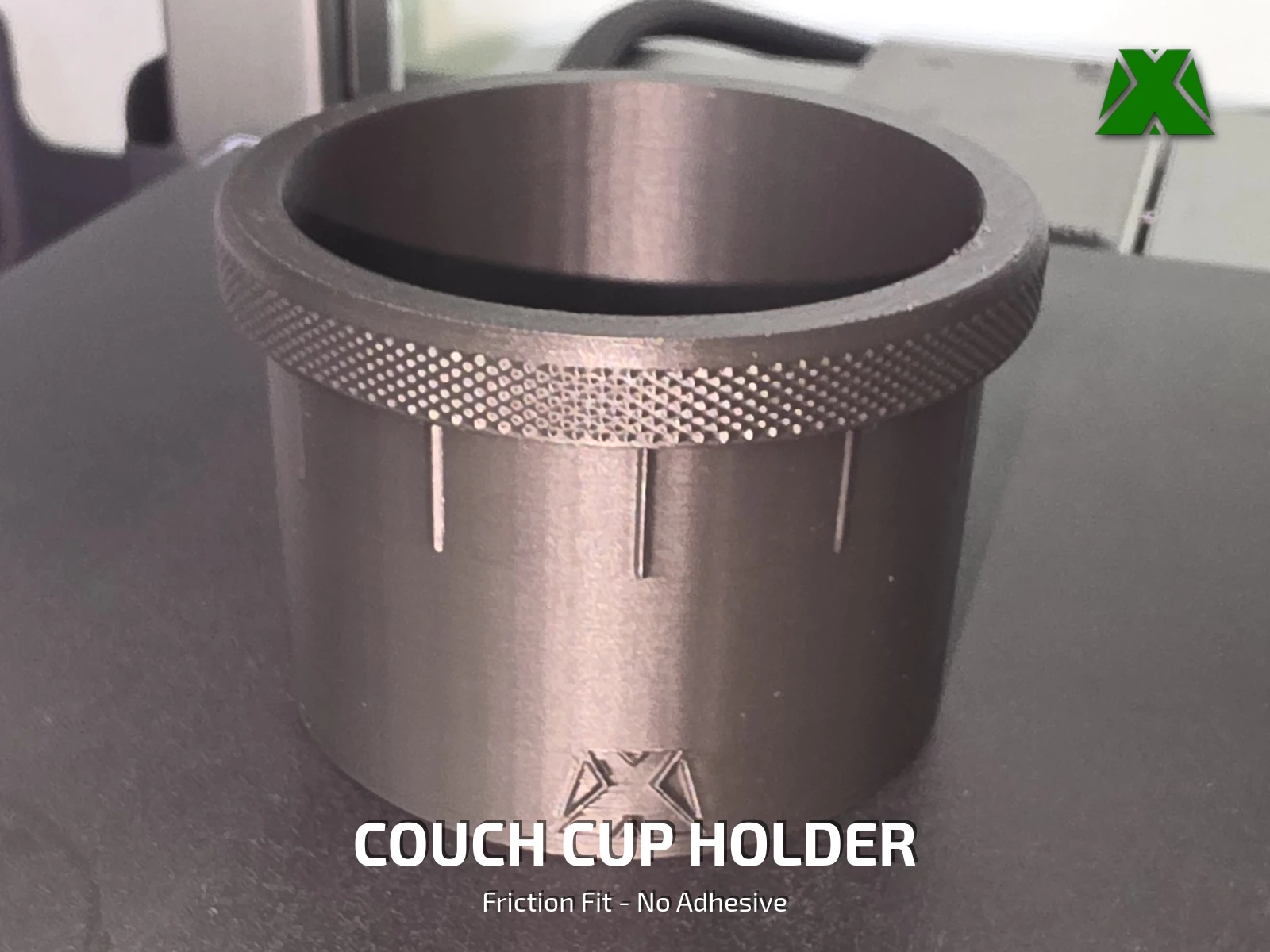 The finished cup holder printed in dark grey PLA, showing the knurled textured lip and the embossed MakerX X