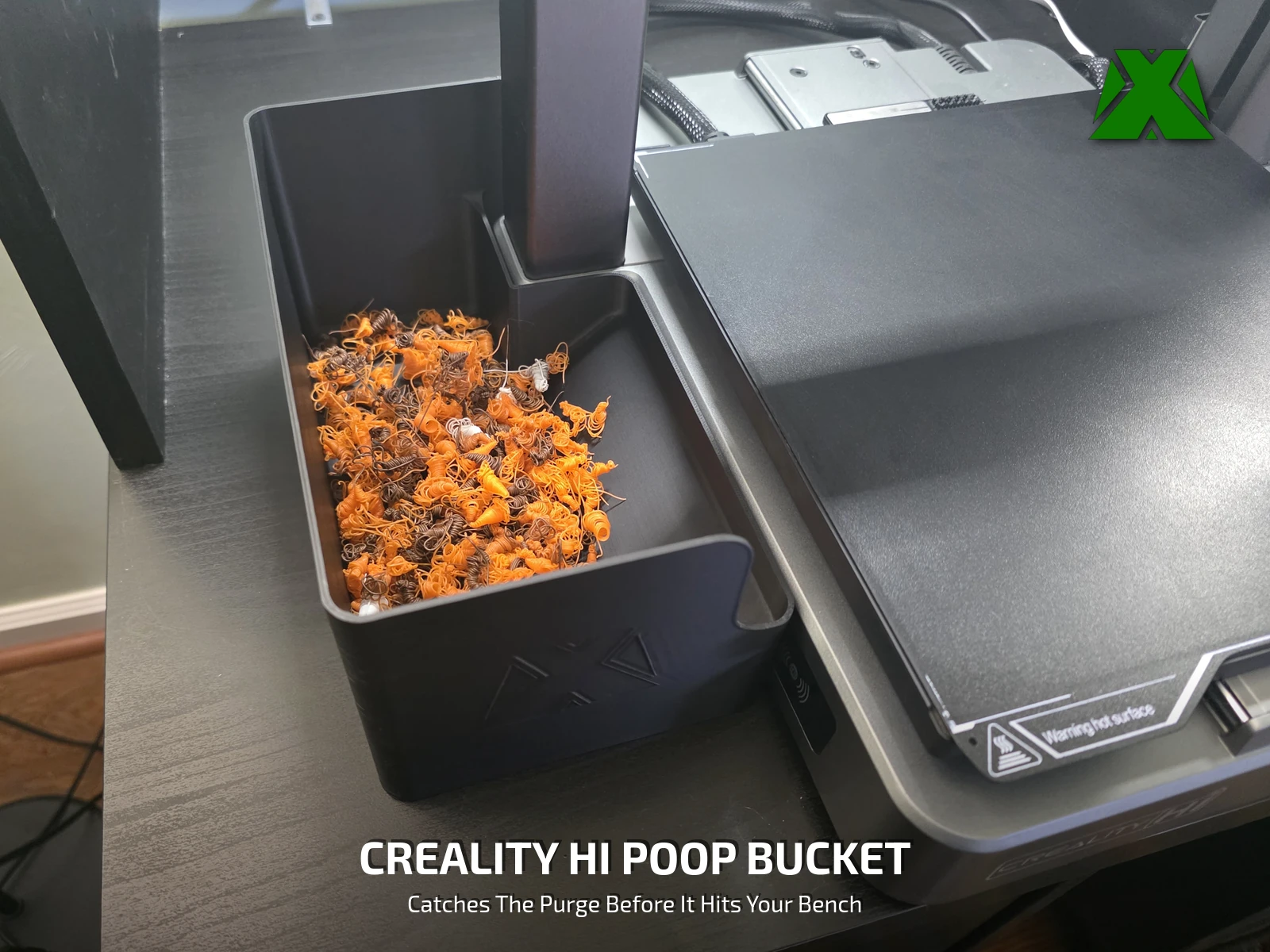The printed bin standing beside a Creality Hi with a pile of orange purge collected in it