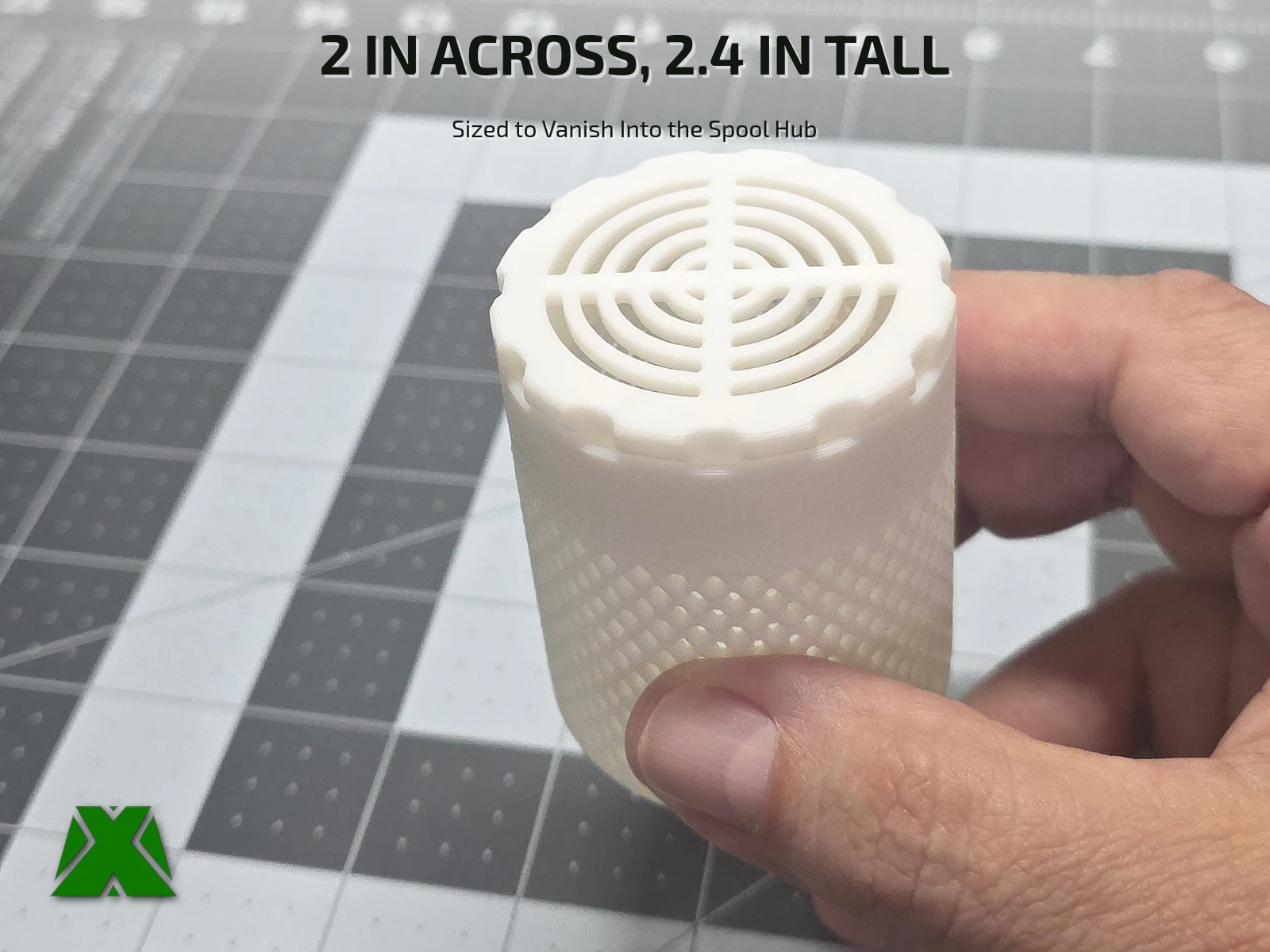 The closed container held between finger and thumb against a cutting mat, showing its concentric-ring lid and overall scale