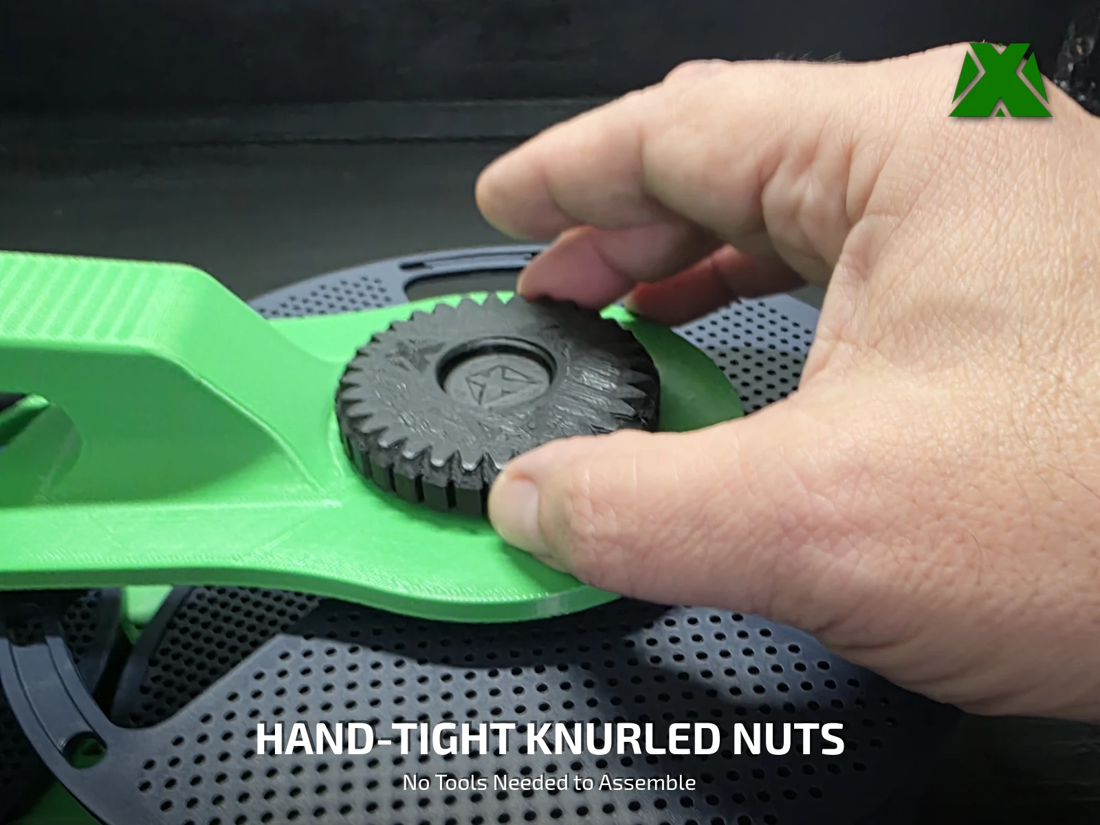 A hand tightening a black knurled nut onto a printed screw on top of the green handle plate
