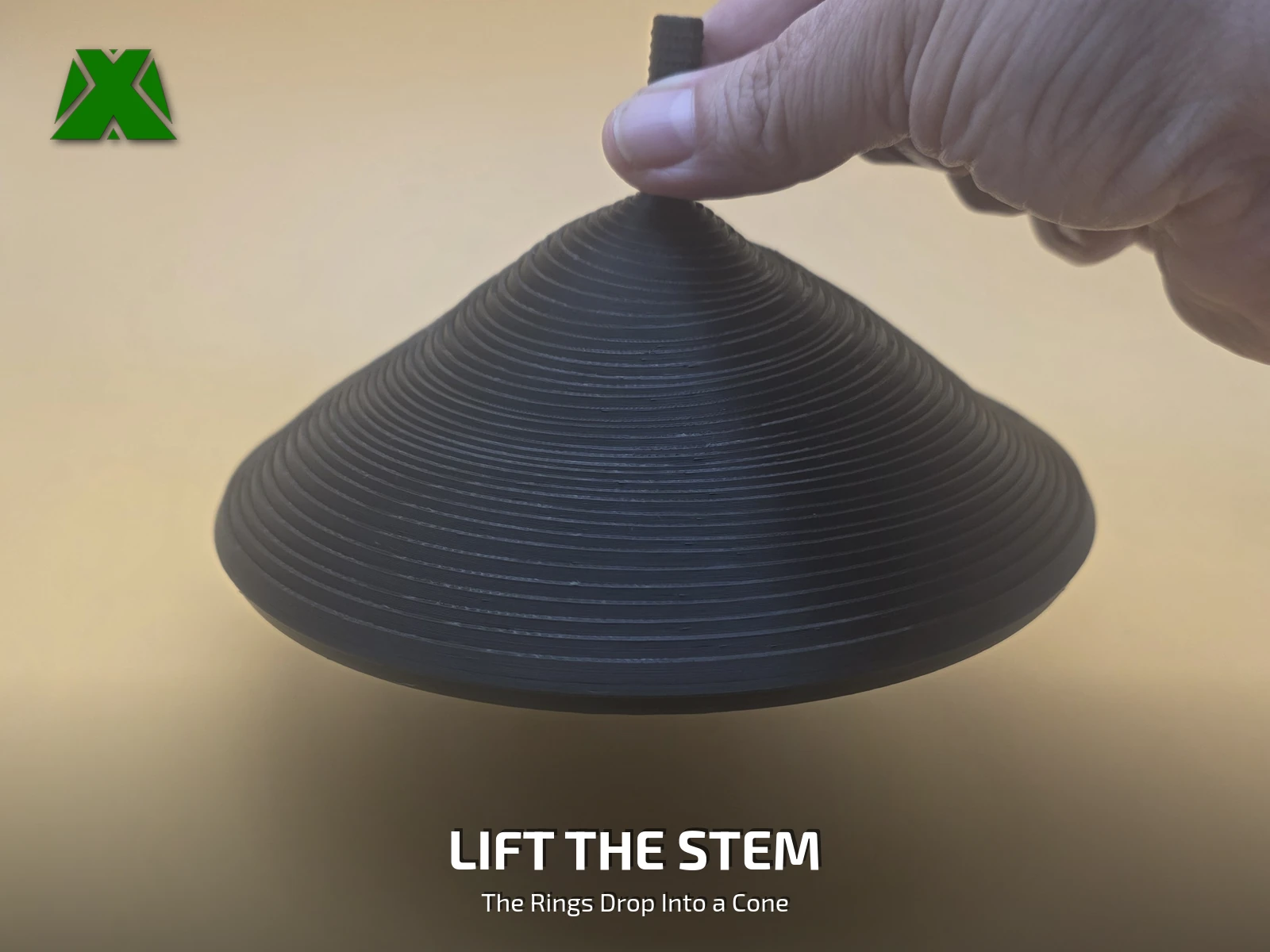 Fingers lifting the fidget circle by its textured stem, the 38 rings hanging below in a smooth cone