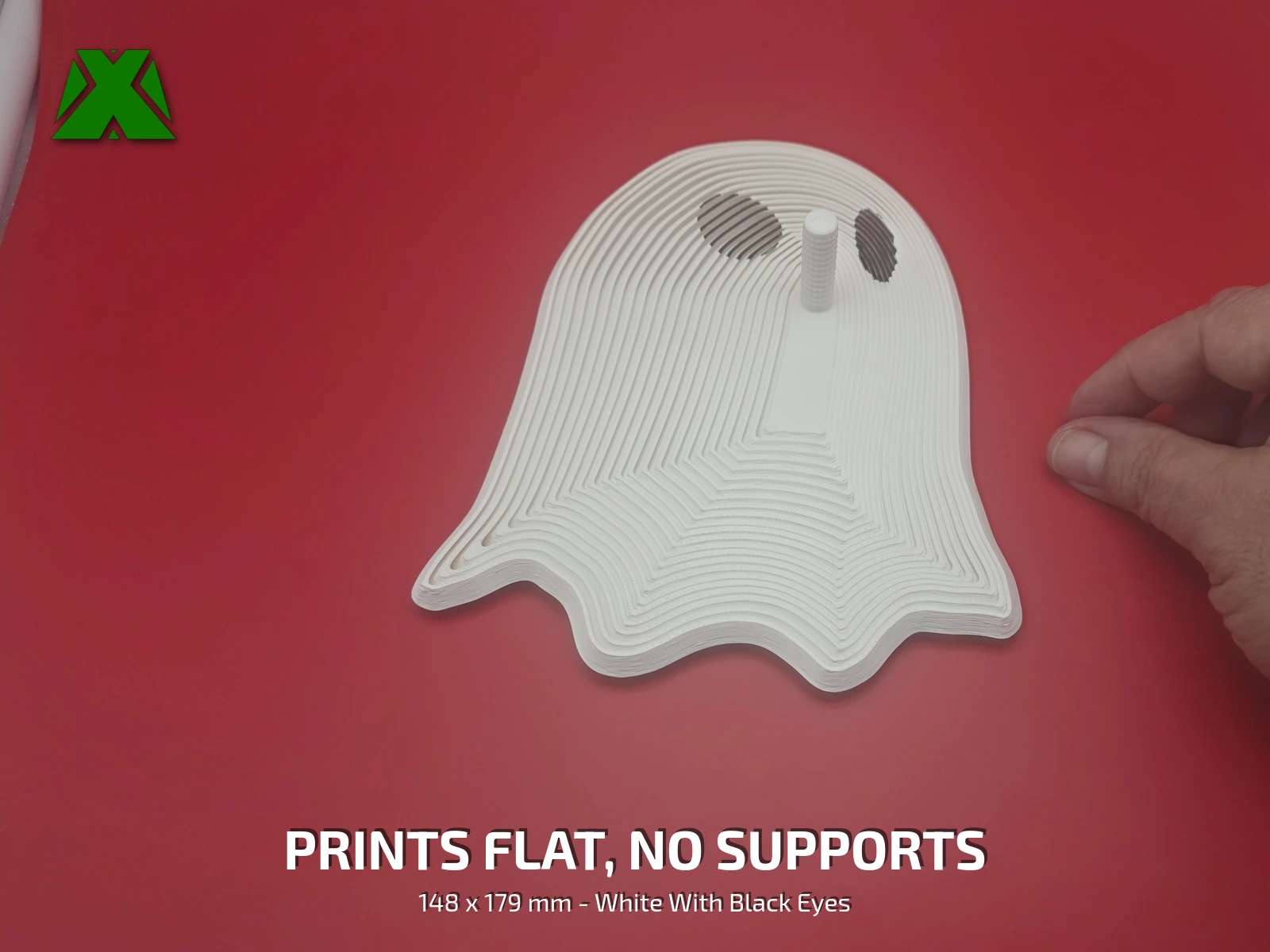 The fidget ghost lying flat on a deep red backdrop with a hand beside it for scale, showing its two dark eyes and wavy hem