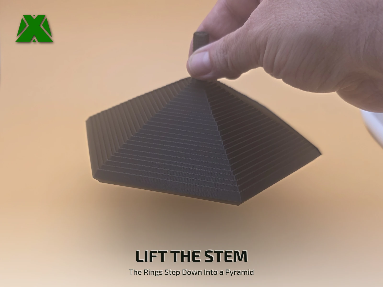 Fingers lifting the fidget hexagon by its textured stem, the 24 rings stepping down below into a six-sided pyramid