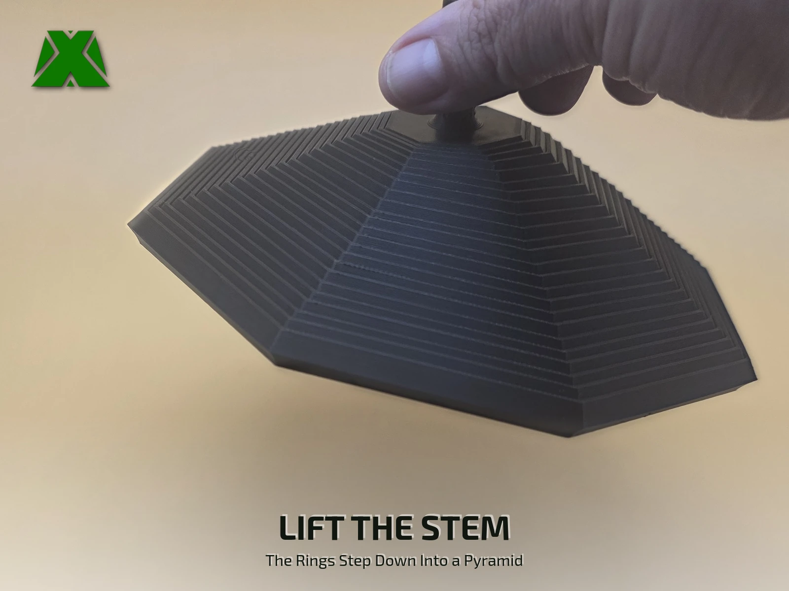 Fingers lifting the fidget octagon by its textured stem, the 23 rings stepping down below into an eight-sided pyramid
