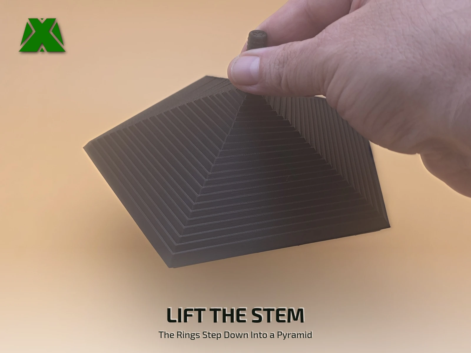Fingers lifting the fidget pentagon by its textured stem, the 22 rings stepping down below into a five-sided pyramid