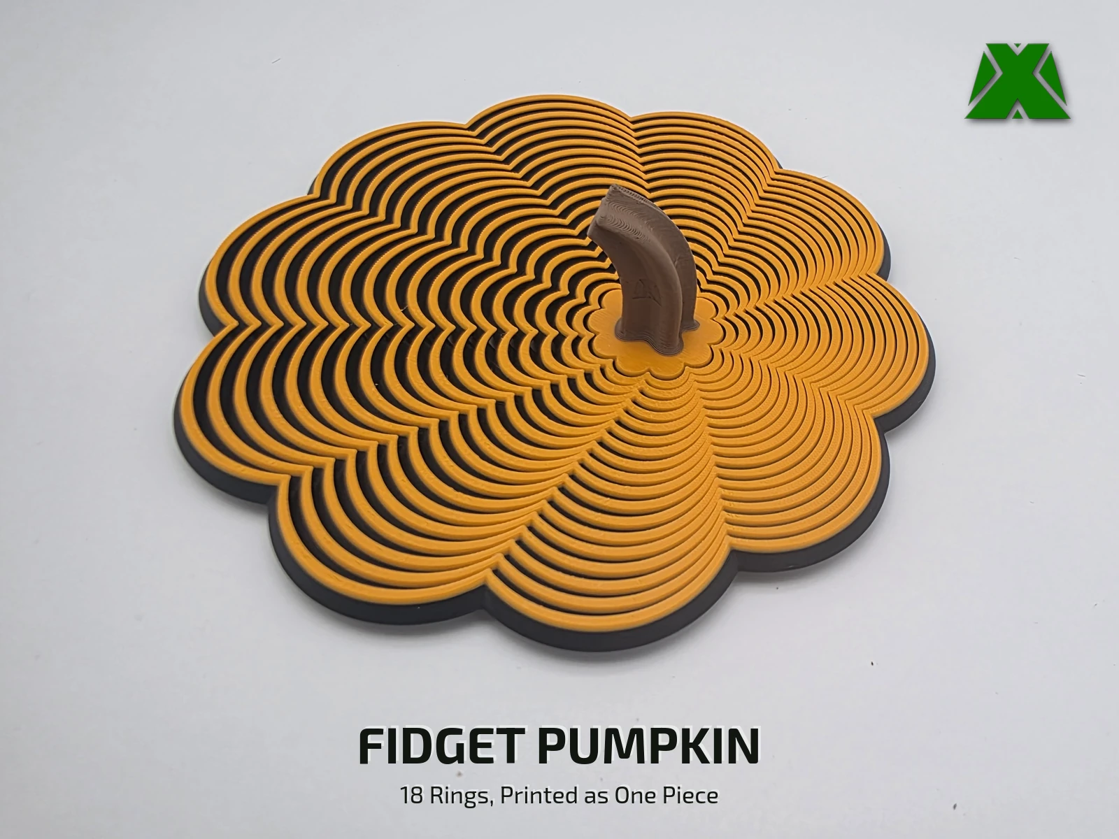 An orange and black fidget pumpkin lying flat on a white backdrop, its brown stem standing up