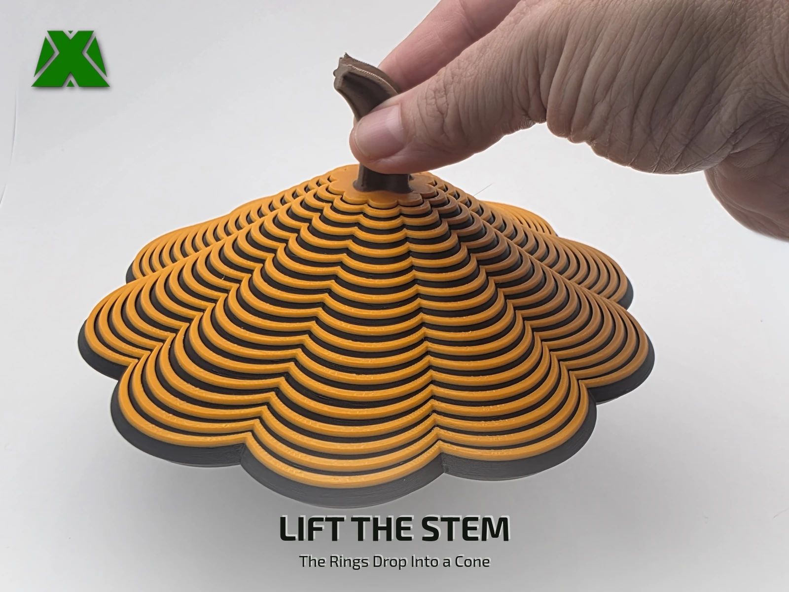 Fingers lifting the fidget pumpkin by its stem, the rings hanging below in a scalloped cone