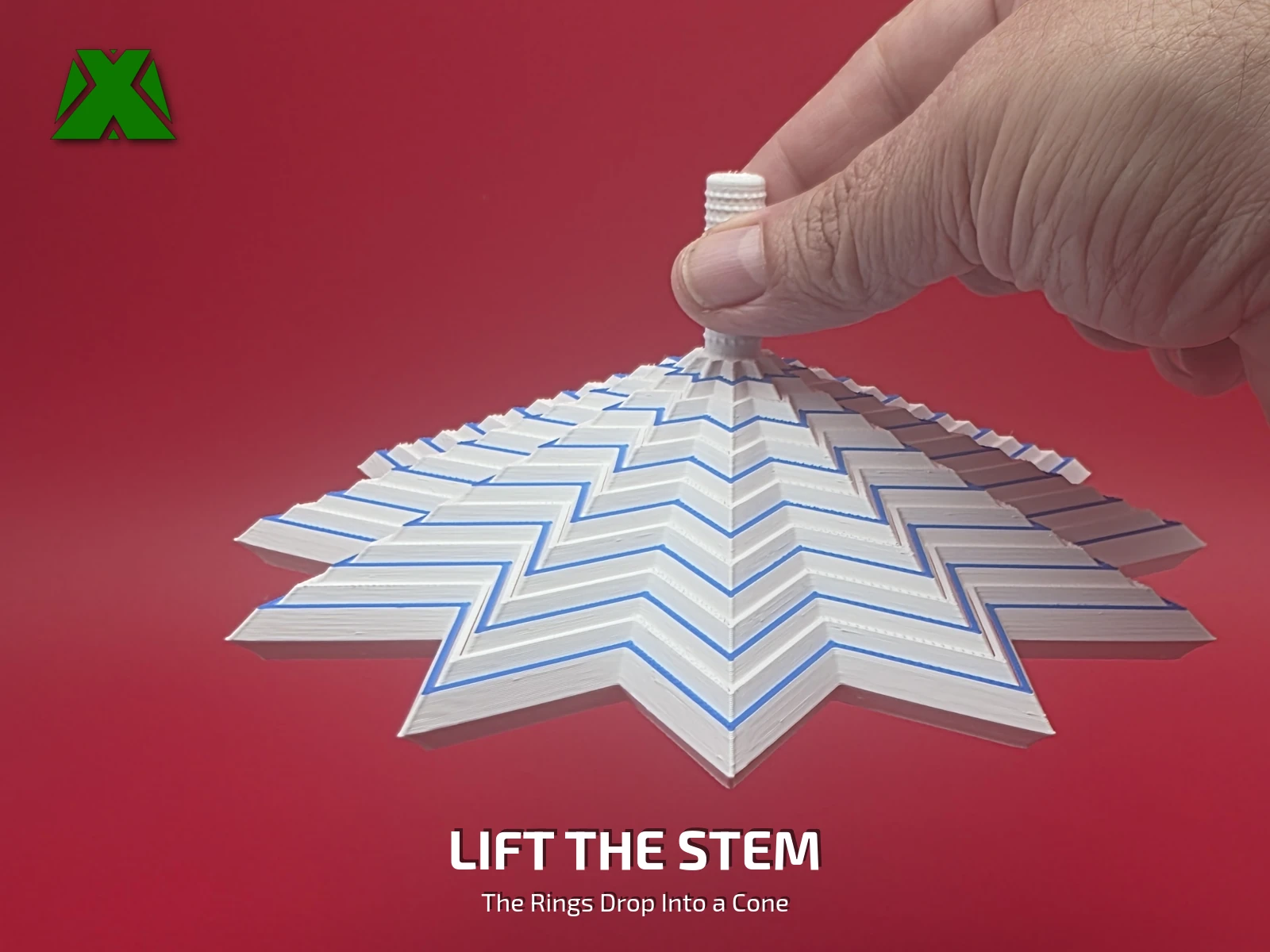 Fingers lifting the fidget snowflake by its textured stem, the blue-striped rings stepping down below into a pointed cone