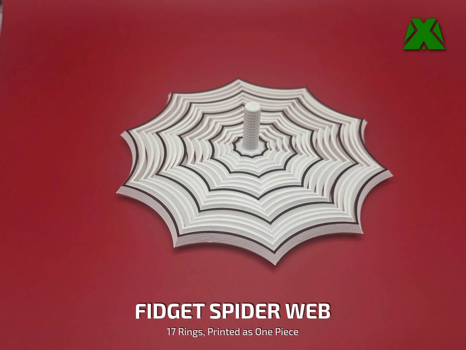 A white fidget spider web lying flat on a deep red backdrop, its scalloped rings ringed by black web lines, with a textured stem standing up at the center