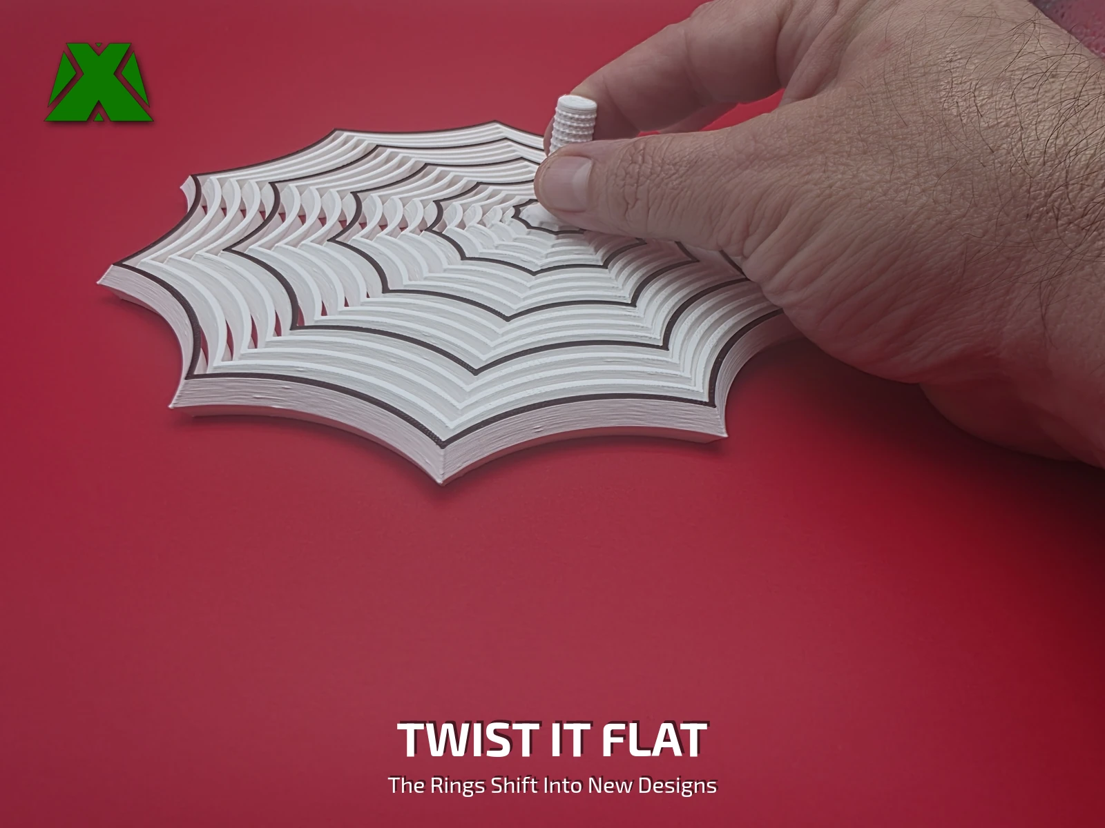 A hand twisting the stem with the web flat on the desk, the rings swept around off-center into a new pattern