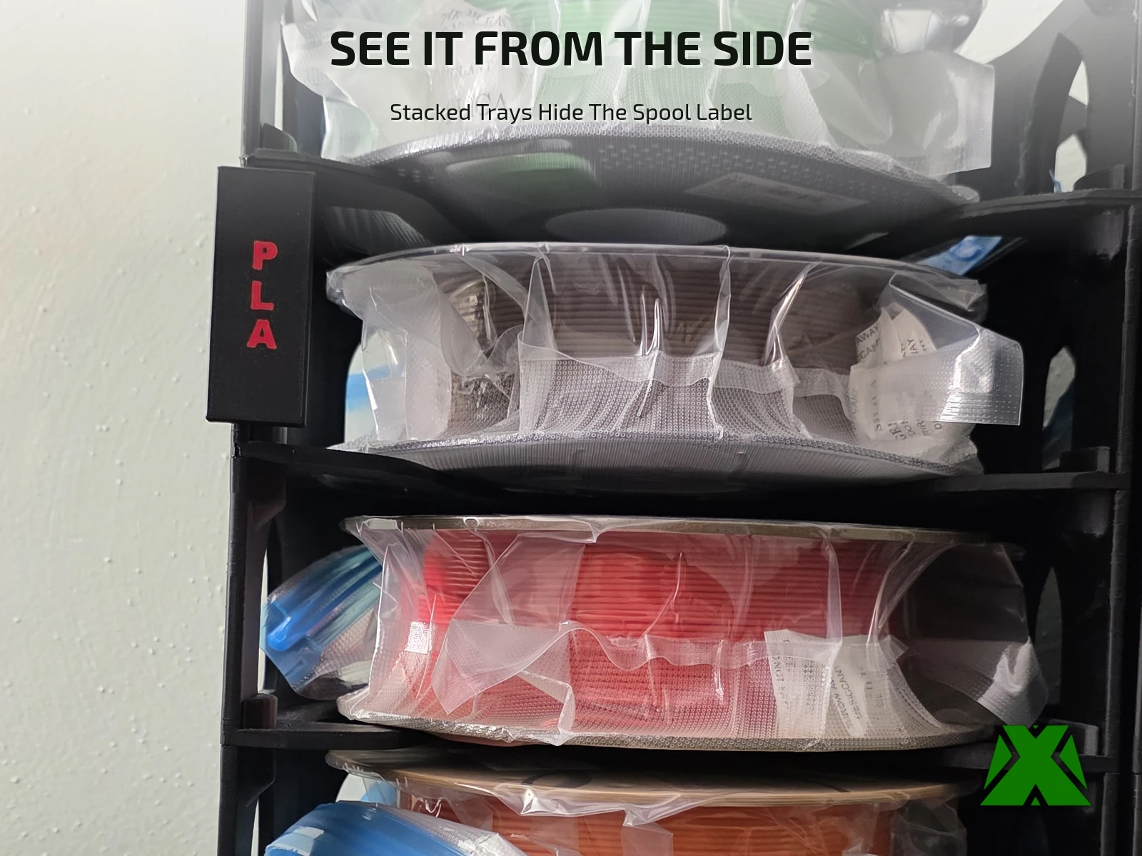 A red-on-black PLA label clipped to the outer wall of a loaded filament storage stack