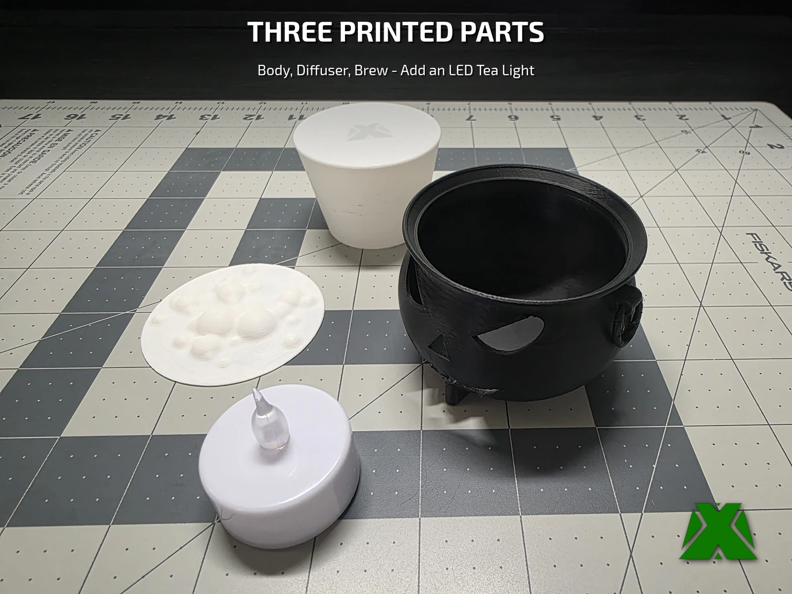 The three printed parts laid out on a cutting mat beside an LED tea light