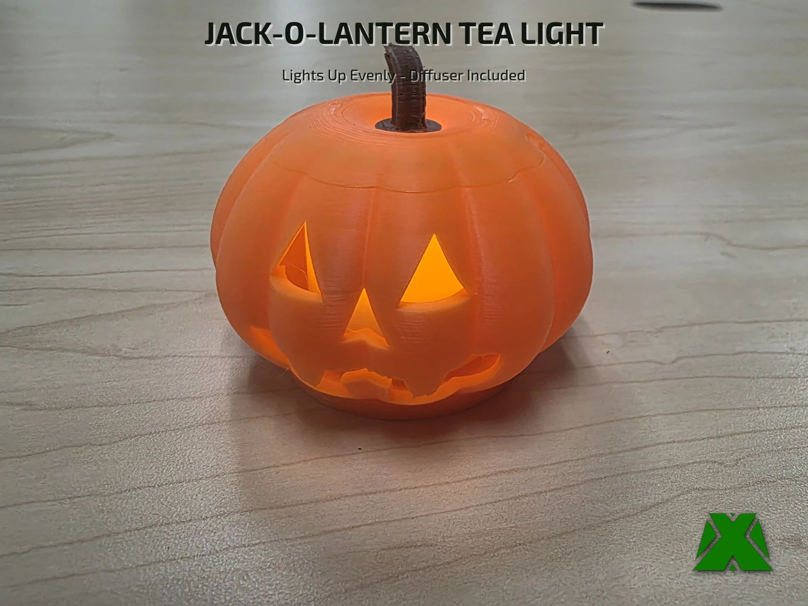 The printed jack-o-lantern lit from inside by an LED tea light, its eyes, nose and mouth glowing orange on a maple desk