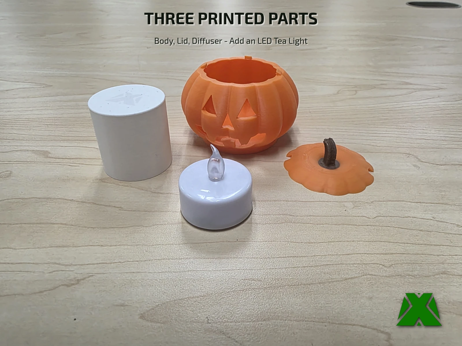 The three printed parts laid out on a desk beside an LED tea light: the white cylindrical diffuser, the pumpkin body and the stemmed lid