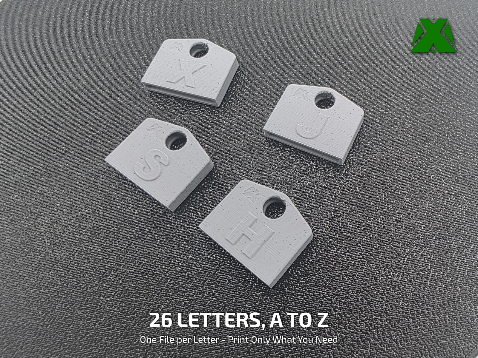 Four gray key covers lying flat on a black textured surface, lettered X, J, S and H