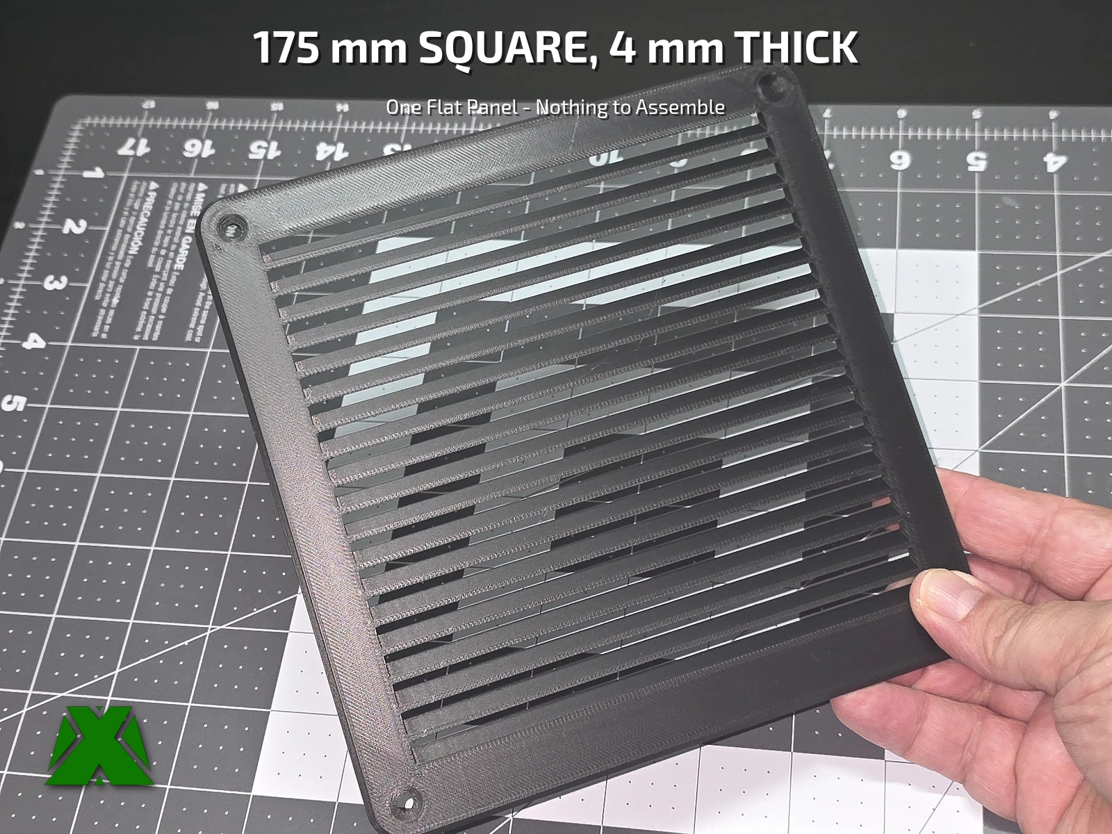 The printed panel held up against a cutting mat, showing the full louver stack and the countersunk hole in each corner