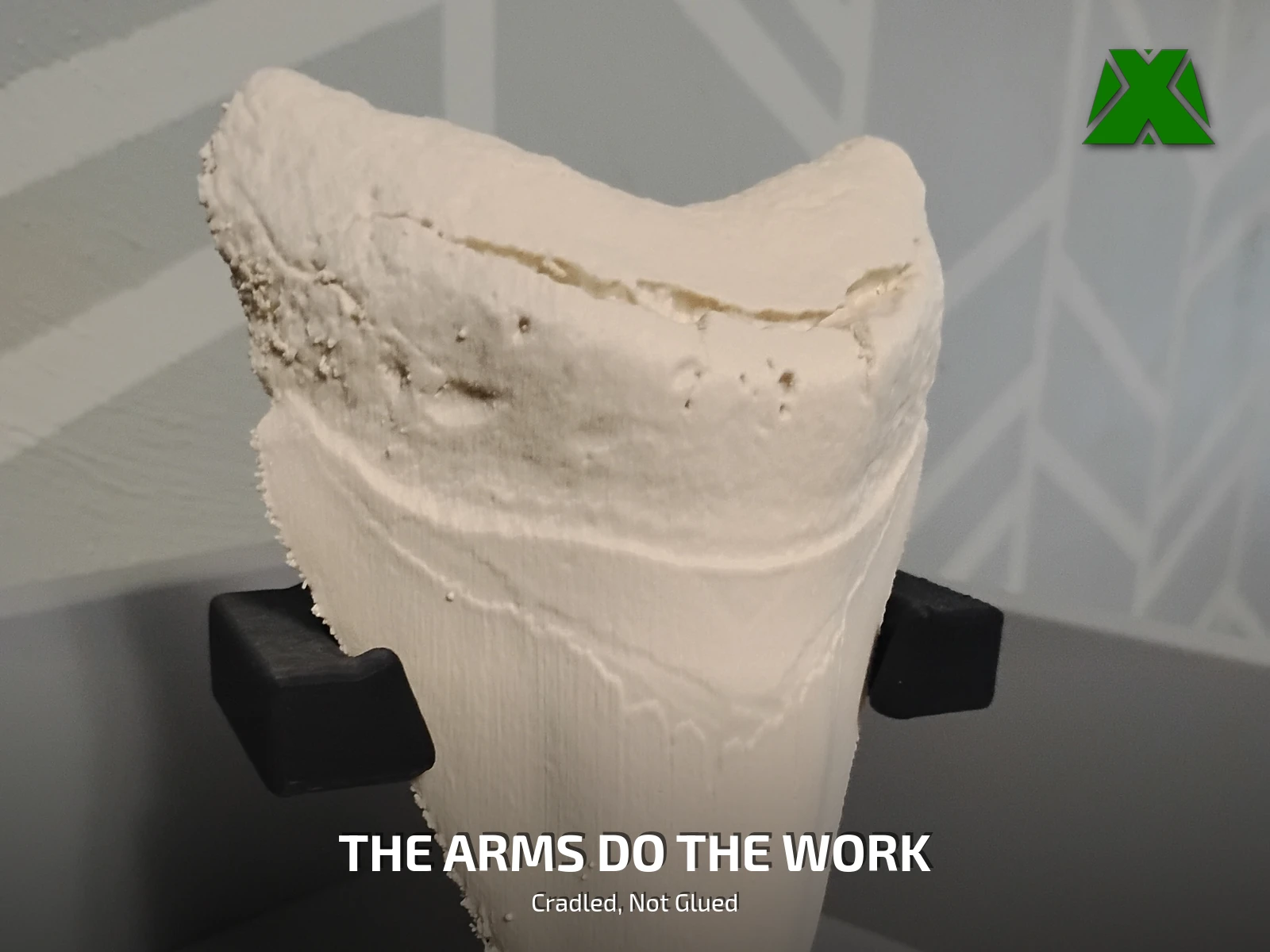 Close view of the two black arms supporting the tooth under its shoulders, with no clamp or adhesive touching it