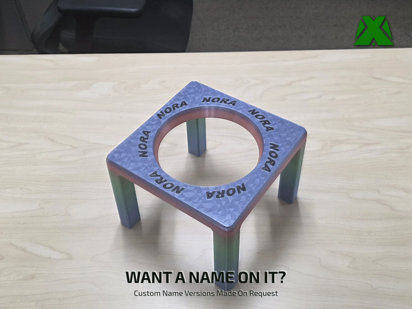 A riser printed in color-shifting filament with the name NORA repeating around the opening