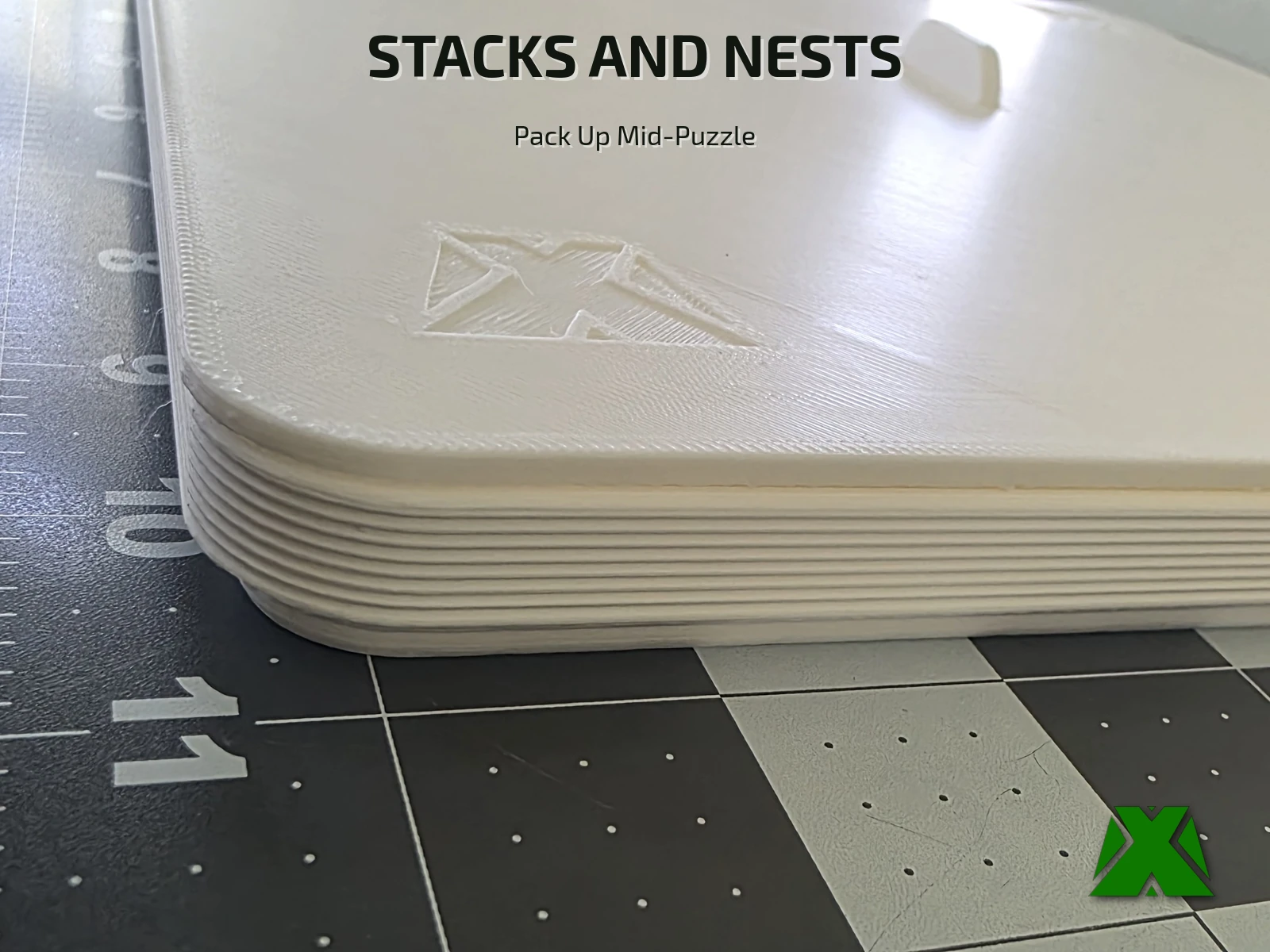 A stack of trays nested together, showing the embossed MakerX X and the lid tab