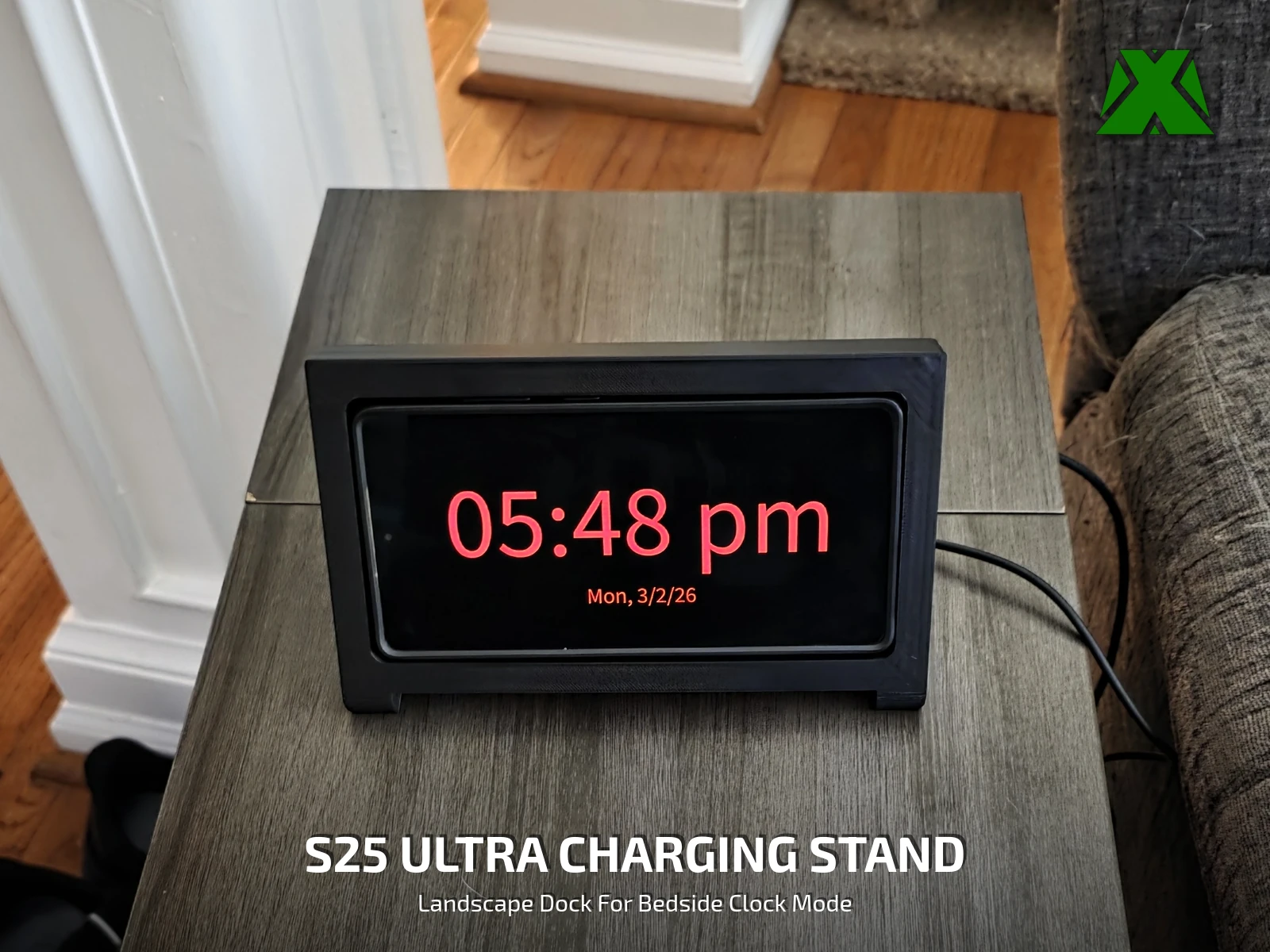 The phone docked sideways in the printed stand on a side table, showing the time