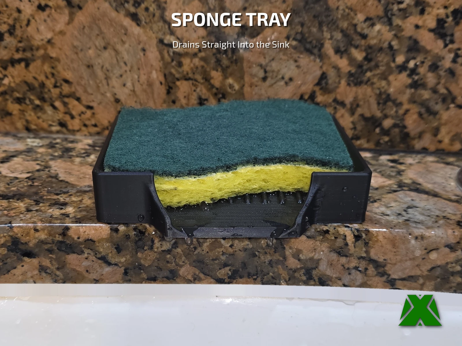 A green and yellow scrub sponge sitting in a black tray on a granite counter behind a white sink
