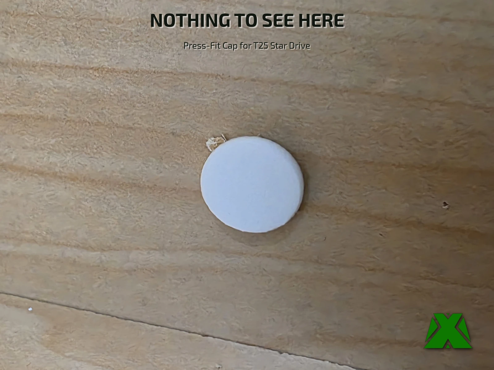 A white printed cap seated flush in a plywood panel, covering the screw head underneath it
