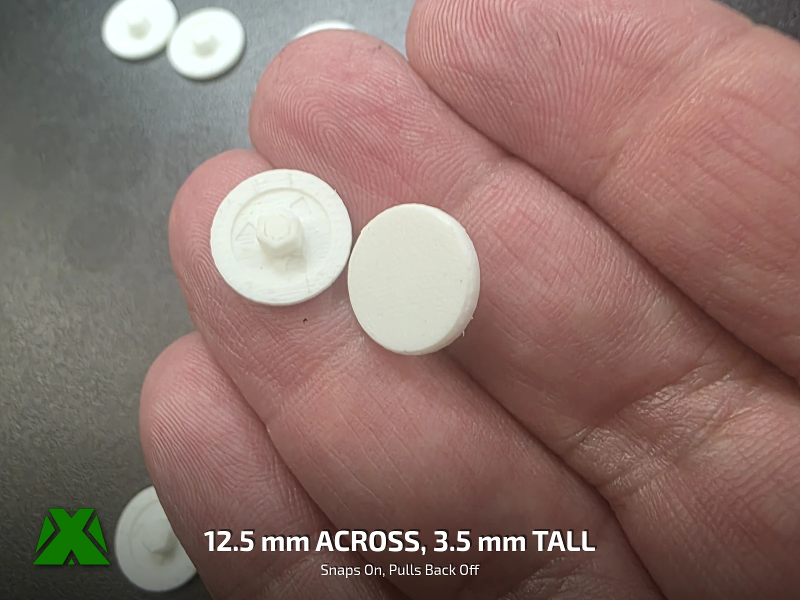 Two caps in an open palm, one showing the star-shaped press-fit boss and one turned over to show the plain face