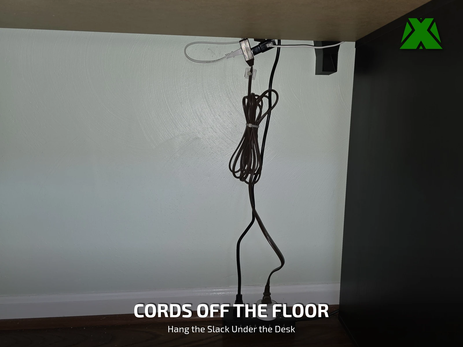 Power cords coiled and hung from a clip under a desktop, the floor below clear